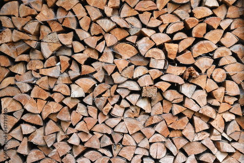 Firewood stacked near the wooden wall of old hut. Many chopped logs of firewood close up