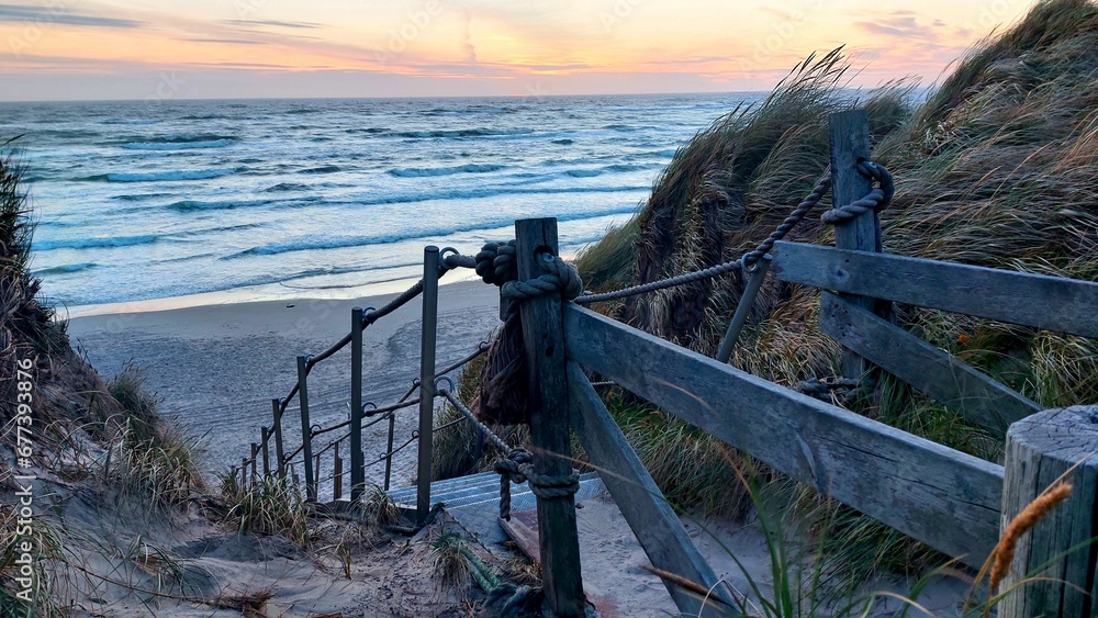 Wooden staircase on the seashore at sunset with a cloudy sky in the background