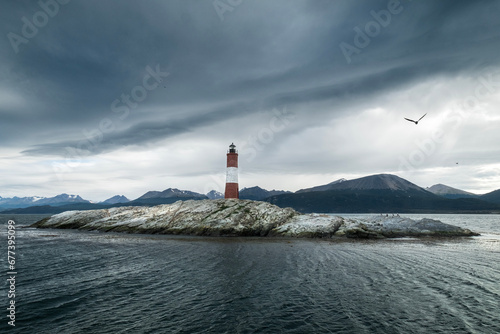 Panoramic view of the rocky island where the Les Eclaireurs lighthouse is located, under a cloudy sky and the mountains in the background. Ushuaia, Tierra del Fuego, Argentina