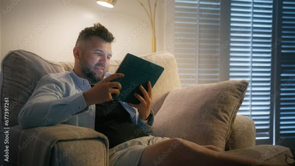 Handsome male scrolling social media, having good time, relaxing in soft chair at home. Mature man searching films to watch for fun online, choosing movies on internet streaming service in living room Handsome male scrolling social media, having good time, relaxing in soft chair at home. Mature man searching films to watch for fun online, choosing movies on internet streaming service in living room