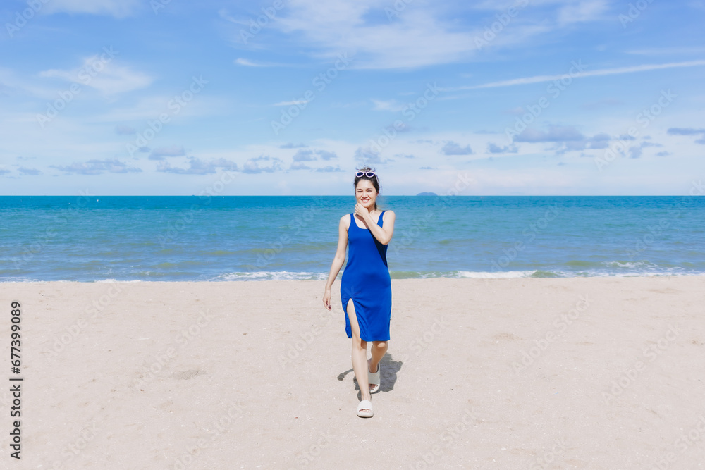 Happy and cheerful woman in blue dress on the sunny beach of Thailand.