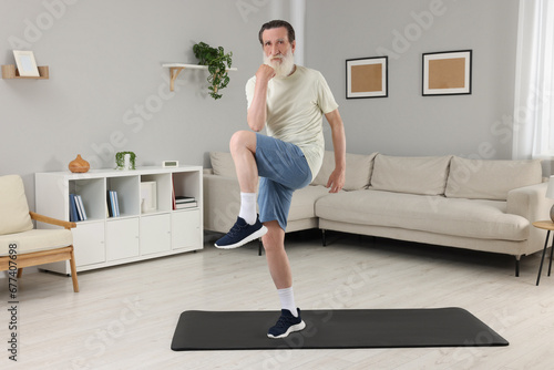 Senior man in sportswear doing exercises at home