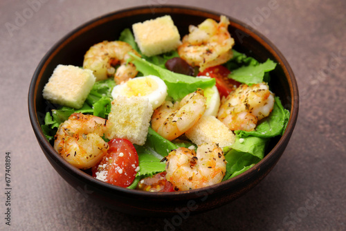 Delicious Caesar salad with shrimps on brown table, closeup
