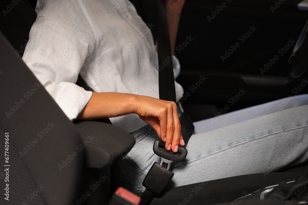 Woman fastening safety seat belt in car, closeup