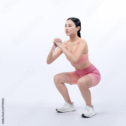 Vigorous energetic woman doing exercise. Young athletic asian woman strength and endurance training session as squat workout routine session. Full body studio shot on isolated background.