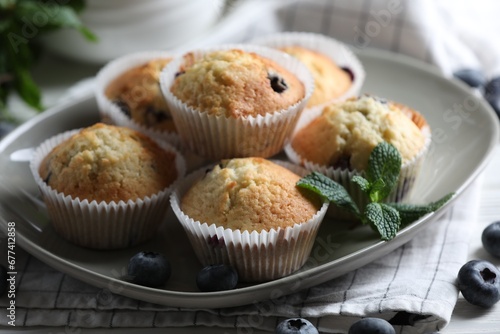 Delicious sweet muffins with blueberries and mint on table, closeup