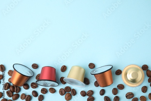 Many coffee capsules and beans on light blue background, flat lay. Space for text photo
