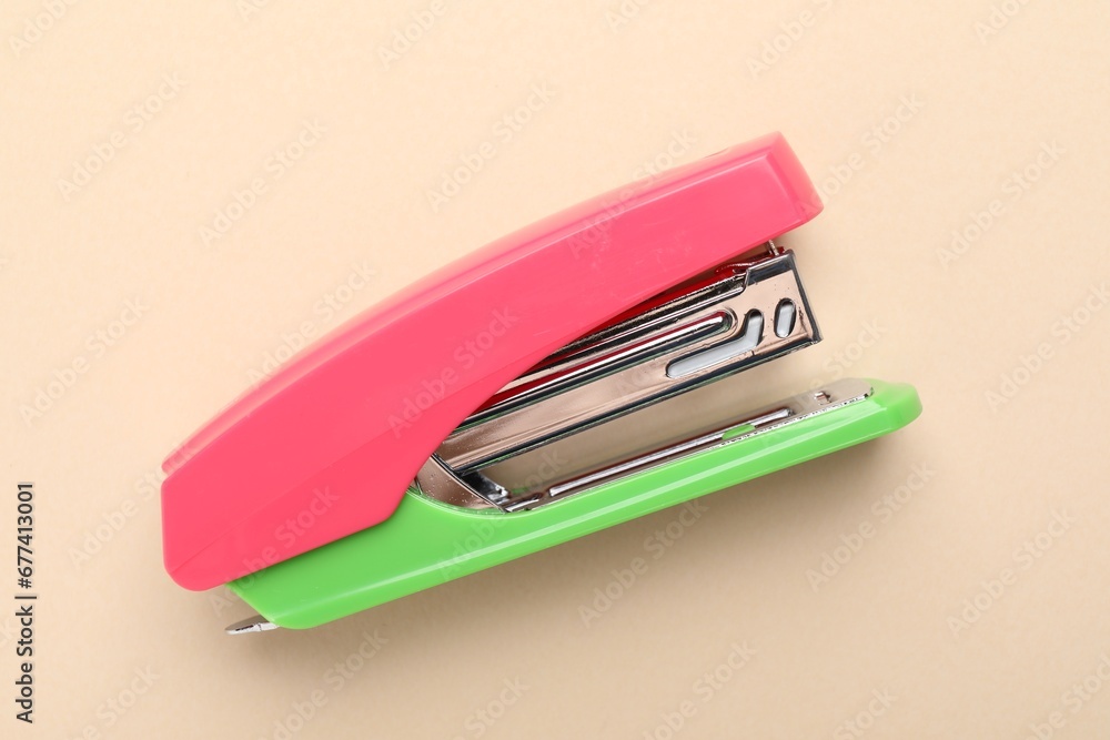One bright stapler on beige background, top view One bright stapler on beige background, top view