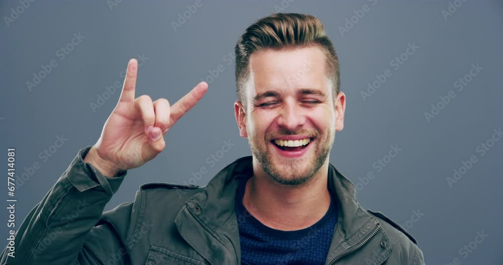 Rock hand gesture, smile or face of man in studio on grey background for freedom, energy or emoji. Happy, male model or portrait of crazy person isolated for devil horns sign, punk or edgy attitude Rock hand gesture, smile or face of man in studio on grey background for freedom, energy or emoji. Happy, male model or portrait of crazy person isolated for devil horns sign, punk or edgy attitude