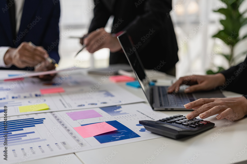 Team of business people working with Paperwork on a table in a conference room in a business presentation or seminar. The document contained financial or marketing figures, graphs, and charts with a l Team of business people working with Paperwork on a table in a conference room in a business presentation or seminar. The document contained financial or marketing figures, graphs, and charts with a l