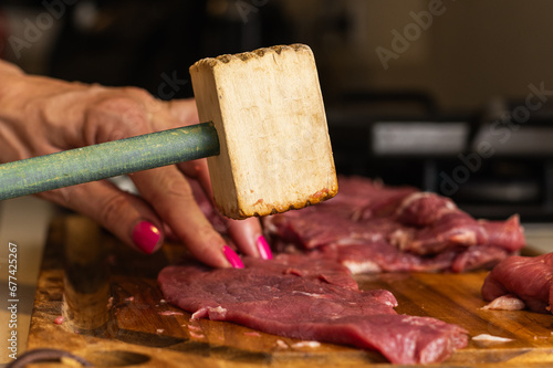 a photograph with raw meat cut into steaks to make cordovan tenderloins with a knife and a close-up of a hand cleaning or tenderizing the meat photo