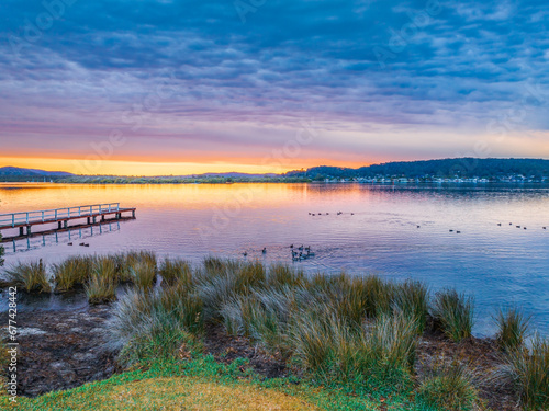 Heavy cloud covered sunrise over the bay with lots of ducks