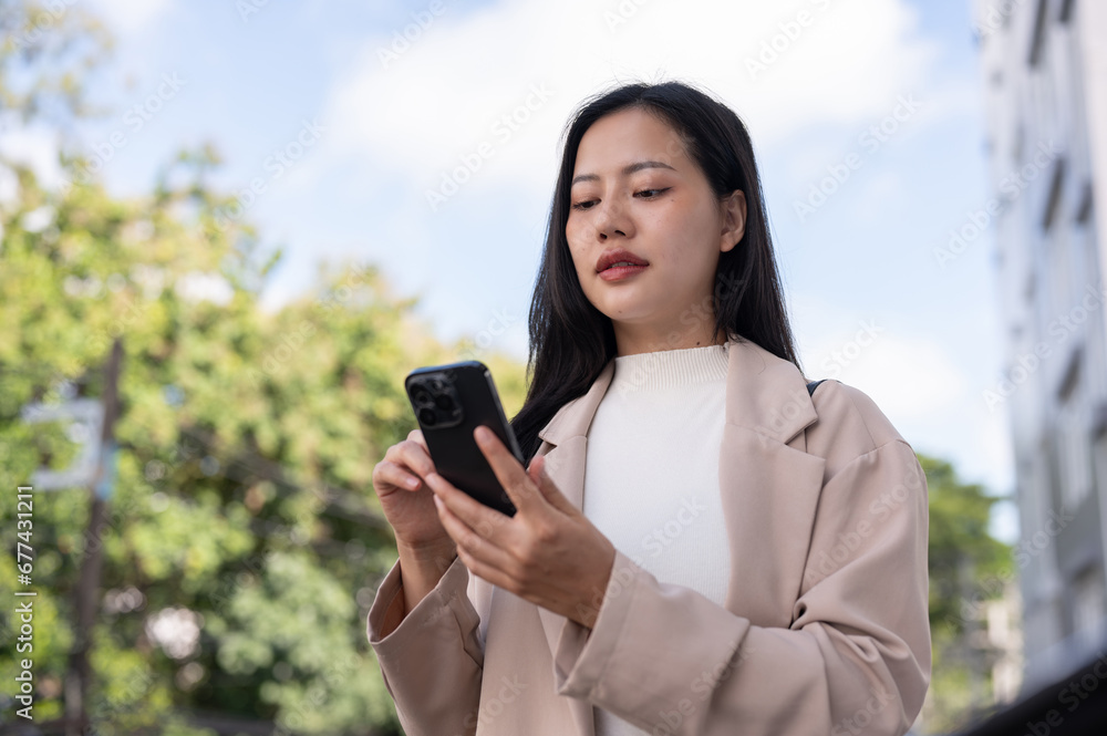 A beautiful Asian businesswoman is using her phone, checking messages while walking in the city. A beautiful Asian businesswoman is using her phone, checking messages while walking in the city.