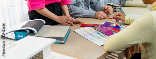 Interior designer team present color selection to project manager with color swatches and architectural model on meeting table. Creative working and design concept. Focus on hand. Variegated.