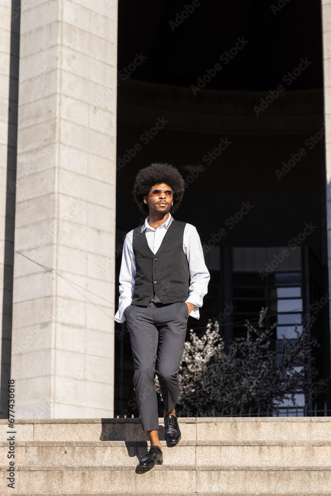 Latin boy with curly hair dressed elegant for a wedding walking down the stairs outside the church. Vertical photo Latin boy with curly hair dressed elegant for a wedding walking down the stairs outside the church. Vertical photo