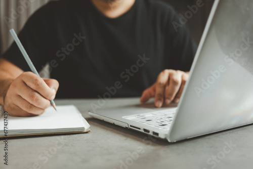 Man writing information on document and checking an order on a monitor screen, freelance doing small business and retail. Taking order for Internet store. Selling online concept ideas. photo
