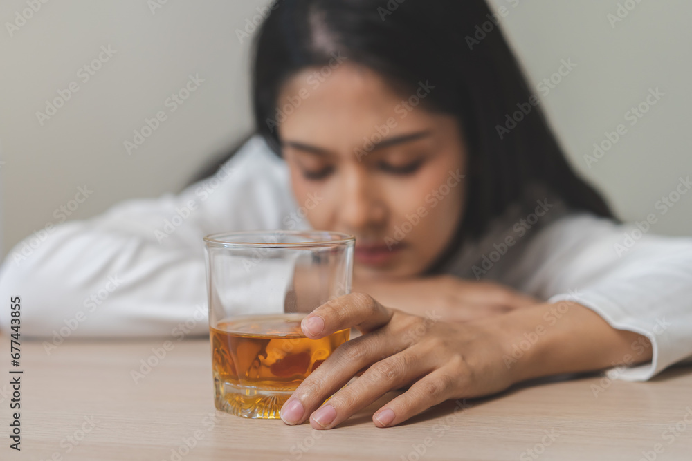 Alcoholism drunk, sad asian young woman fell asleep hand holding glass of alcohol or whiskey, alone depressed alone female drink booze. Treatment of alcohol addiction, suffer abuse problem alcoholism. Alcoholism drunk, sad asian young woman fell asleep hand holding glass of alcohol or whiskey, alone depressed alone female drink booze. Treatment of alcohol addiction, suffer abuse problem alcoholism.
