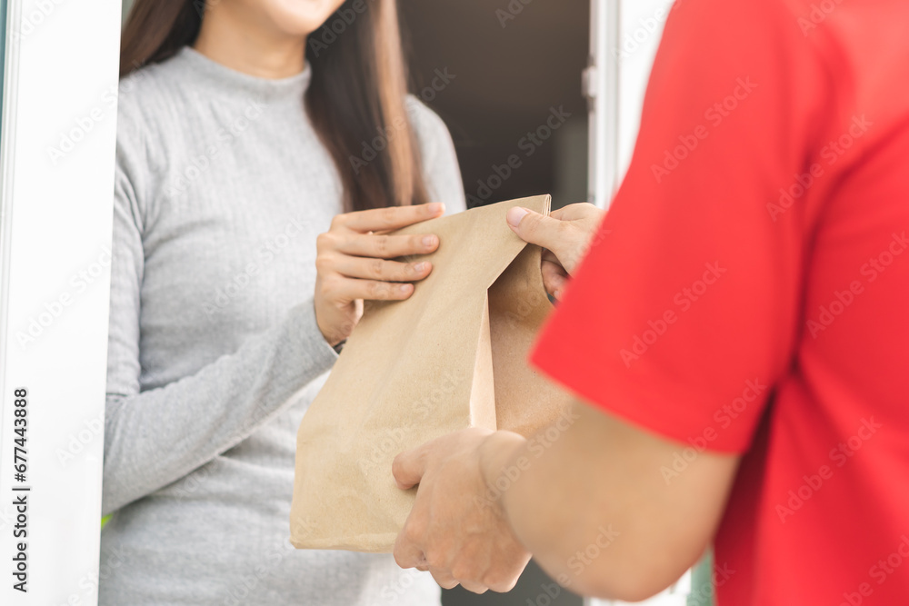 Obraz premium Postman, service fast food asian young woman, girl hand received order, delivery man, male holding, carrying paper bag send to customer house. Courier bring product, takeaway to door, express grocery.