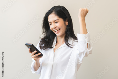 Happy asian young woman using mobile smart phone, read good news online feel excited getting offer, great positive surprise, celebrate success on smartphone. Businesswoman isolated on white background photo