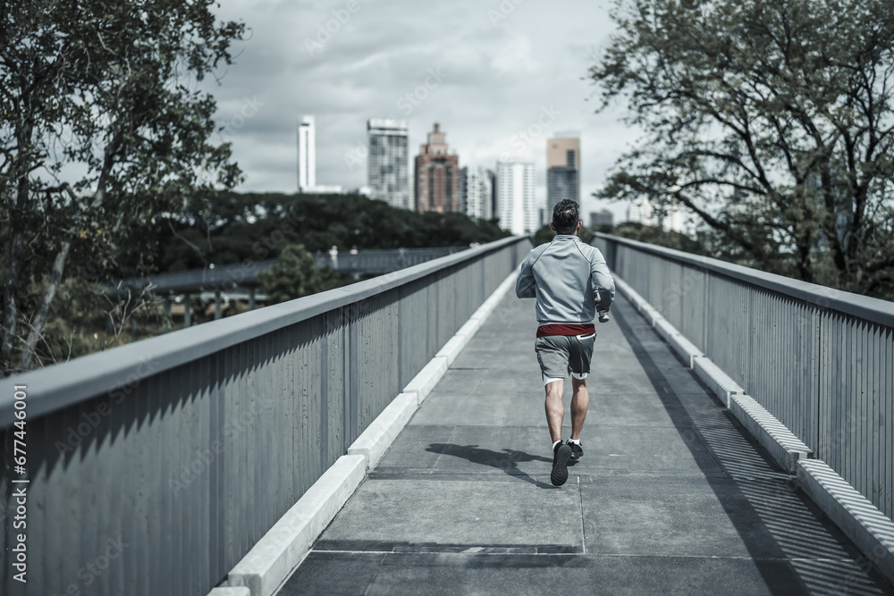 A man running up on footbridge in the city center park for cardio workout.  Health and Lifestyle in big city life concept.