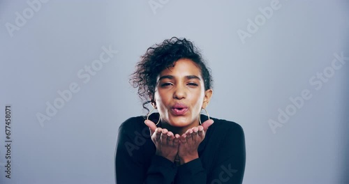 Face, hands and woman blowing kiss in studio for flirting, gratitude and valentines day on grey background. Portrait, model and smile with love emoji, sign and thank you for kindness, pride and care photo