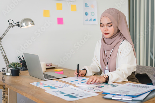 Young Muslim accountant businesswoman analytic business report at workplace.