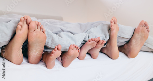 Family, feet and sleeping in bed, morning or relax together with kids and parents under blanket. Foot, closeup or children rest with mom and dad in bedroom with comfort in home on vacation or holiday
