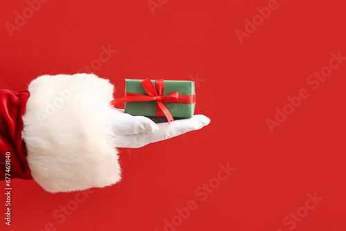 Santa Claus with green gift box on red background