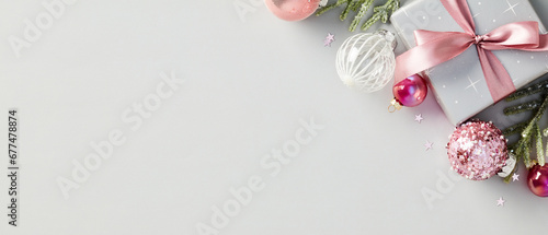 Christmas banner with elegant gift box, festive baubles, and stylish ribbon. Modern design with glitter Xmas ornaments. Luxury holiday composition in pink and grey tones