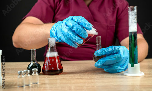 male scientist in lab coat mixing reagents from glass flasks