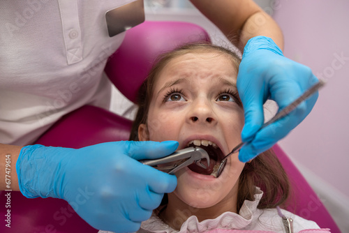 girl with her mouth open looking at dentist while the doctor checks the child's teeth.