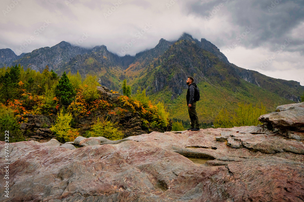 Hiker looking at a cloudy autumnal landscape in Thethi National Park, Albania. 