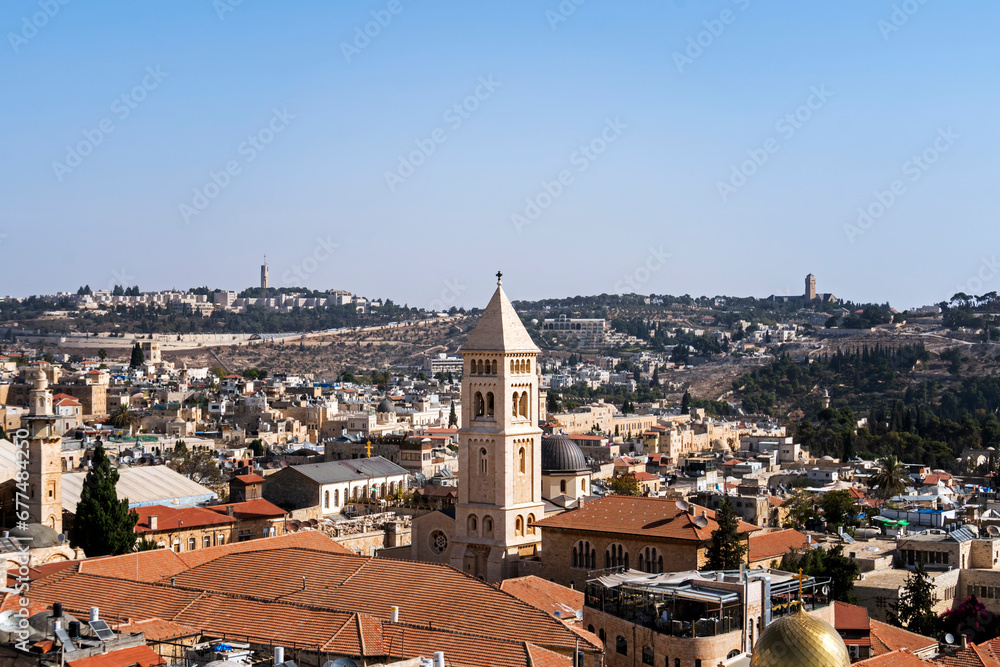 Panoramic view on old part of Jerusalem city, Israel. Ancient jewish city shot from above on a sunny cloudless day. Tiled roofs, chapels and dome of churches of Jerusalem at blue sky background.