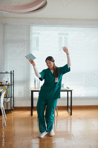 Medical nurse in green scrubs dancing in hospital lounge area after finishing shift