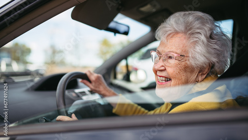 Happy senior woman driving car alone, enjoying car ride. Safe driving for elderly adults, older driver safety. photo