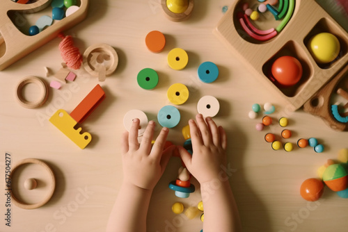 Toddler activity for motor and sensory development, Baby hands with colorful wooden toys on table from above photo