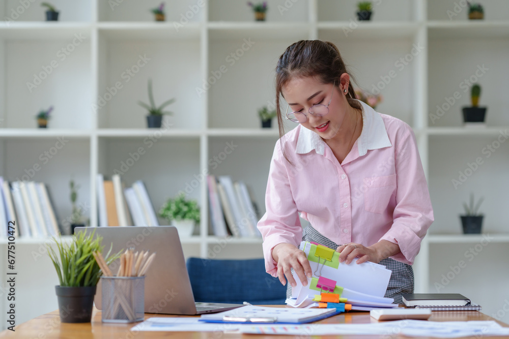 Fototapeta premium Asian woman holding a file and checks documents in the office.