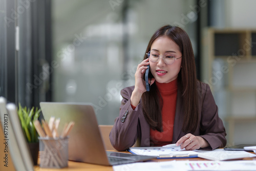 Asian businesswoman talking on the phone professionally in her office.