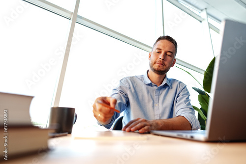 Portrait of young man sitting at his desk in the office and using computer