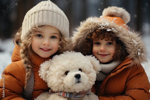 Two girls in warm clothes, jackets and hats, with a large toy bear against the backdrop of a winter landscape. Close-up portrait of children against the backdrop of a snowy forest or park.