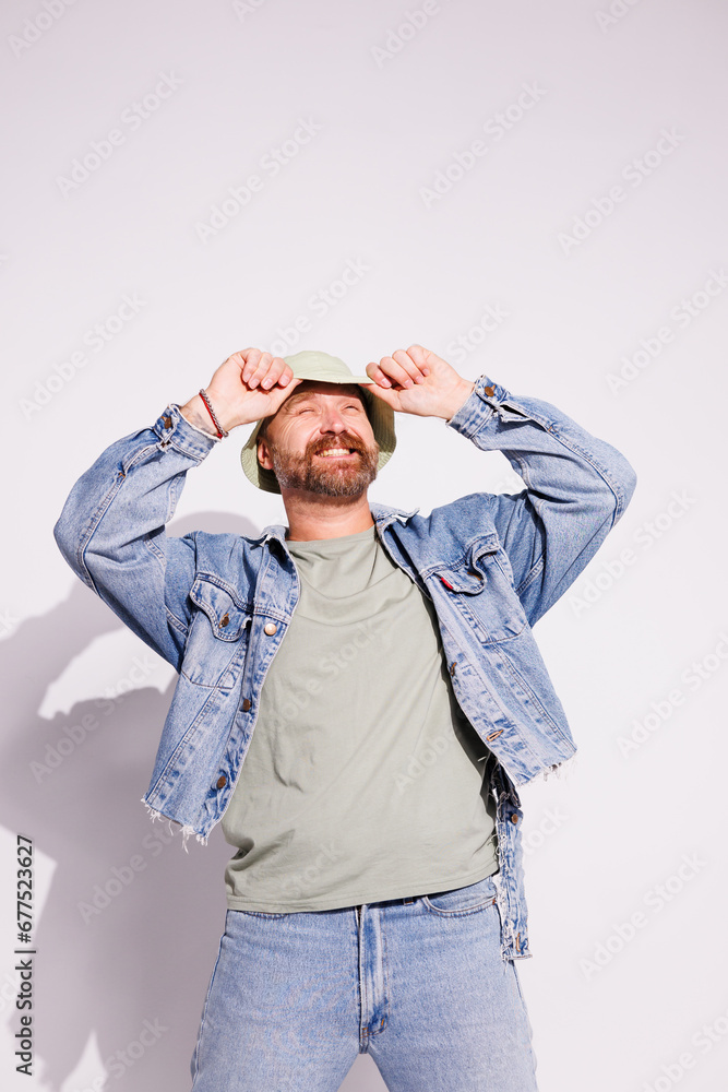 Cheerful and stylish bearded man in denim jacket and bucket hat on grey background Cheerful and stylish bearded man in denim jacket and bucket hat on grey background