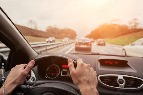 driving, travel by car, hands of car driver on steering wheel,  driving on highway road. photo