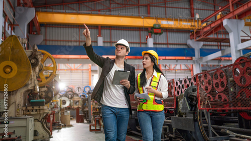 Chief Engineer and Project Manager Wearing Safety Vests and Hard Hats, Use Digital Tablet Computer in Modern Factory, Talking and planning optimization of production at industrial factory.