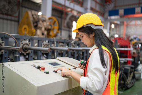Female industrial engineer or factory worker wearing a yellow helmet working in industrial factory.