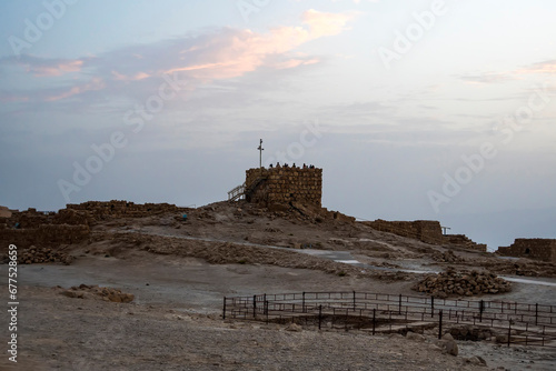 The tallest tower of Masada against the cloudy sky at dawn in the sun. Historical excavations on the ruins of the ancient era. Israel. photo
