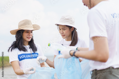 Group of Asian young people volunteer helping to collecting or picking up a plastic bottle garbage on the ground in park. Sustainability and environment conservation concept.