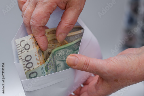 Starsza pani trzyma polskie pieniądze w kopercie 