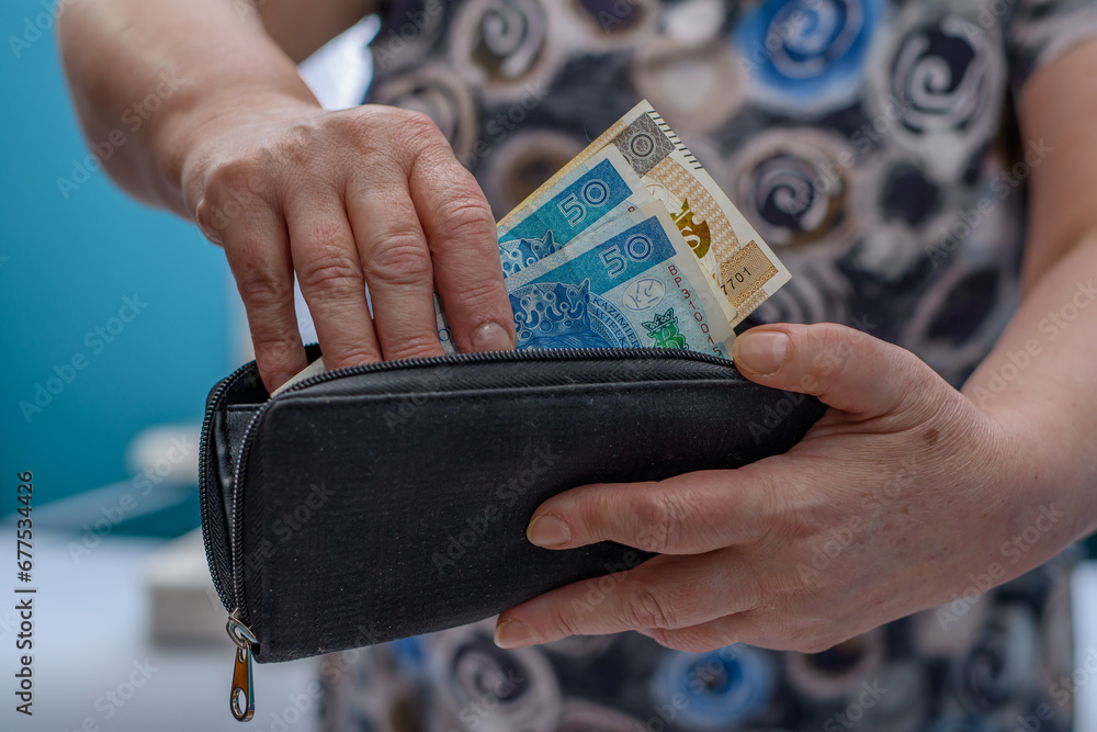 Starsza kobieta płaci pieniądzmi wyjmowanymi z portfela, polskimi banknotami pln - obrazy, fototapety, plakaty 