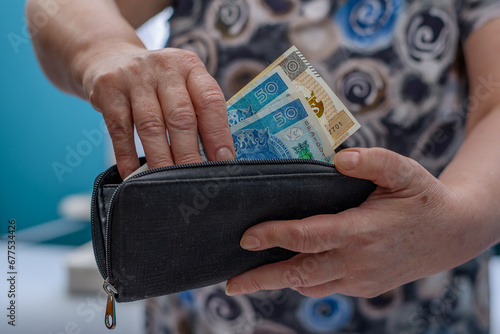 Starsza kobieta płaci pieniądzmi wyjmowanymi z portfela, polskimi banknotami pln photo