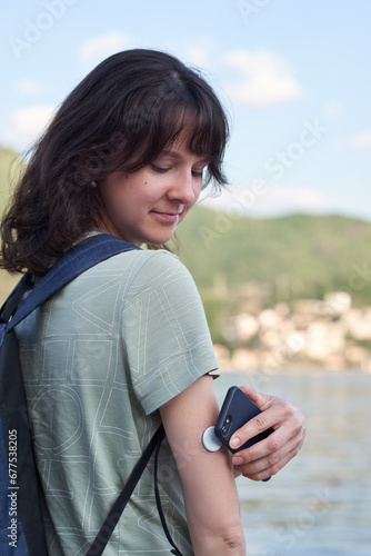 The girl reads the glucose values from the Abbott Freestyle Libre sensor using an application on mobile phone. The latest technology for better life quality for a diabetic.